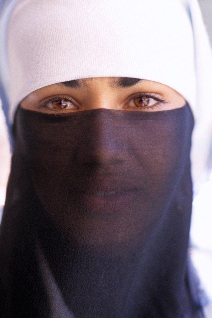A woman wearing a white hat and a black scarf covering her face