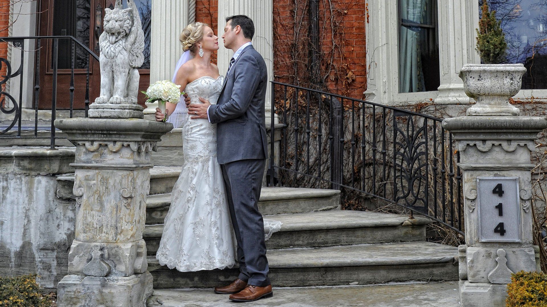 A bride and groom are kissing on the steps of a building.