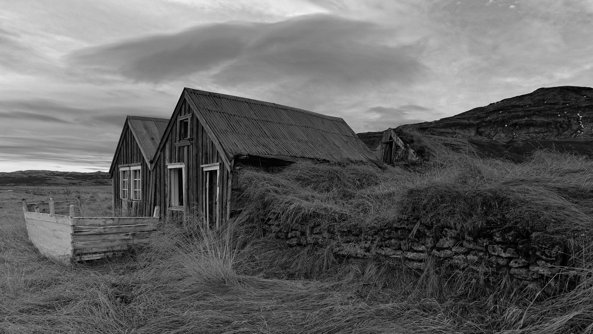 A black and white photo of two houses in a field.
