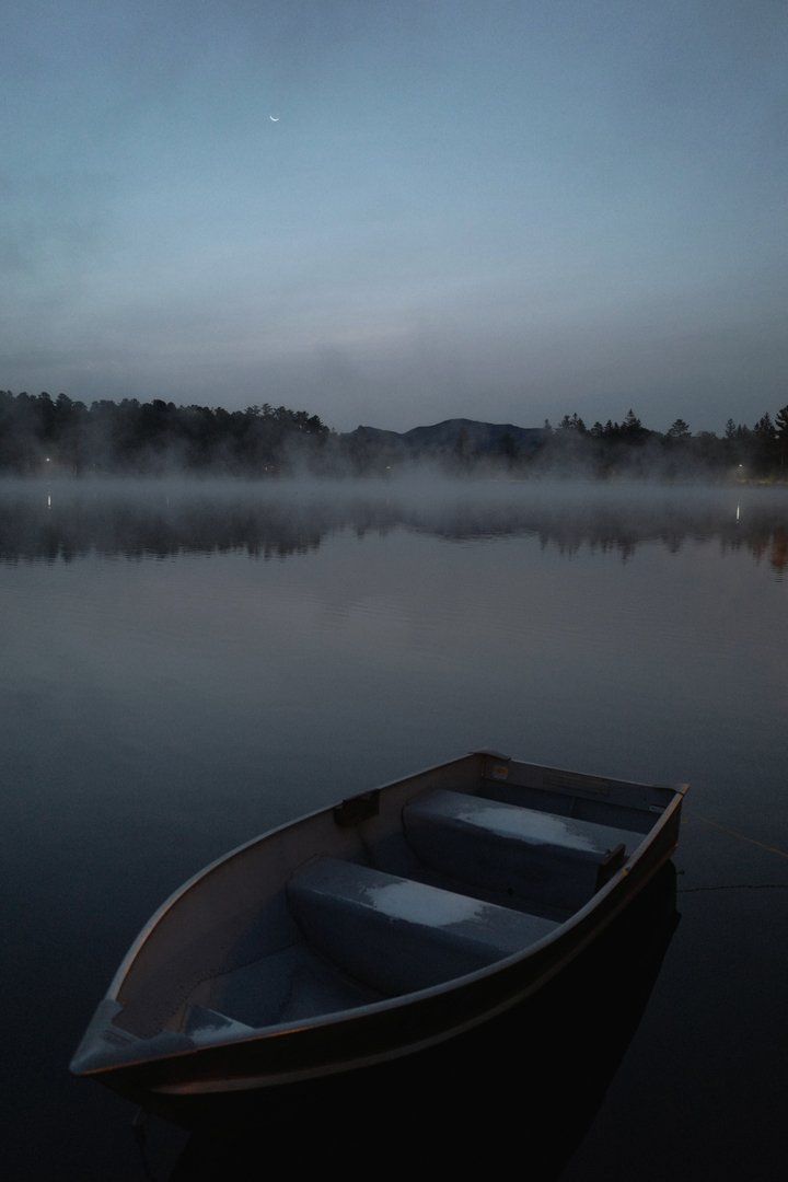 A boat is floating on a foggy lake at night