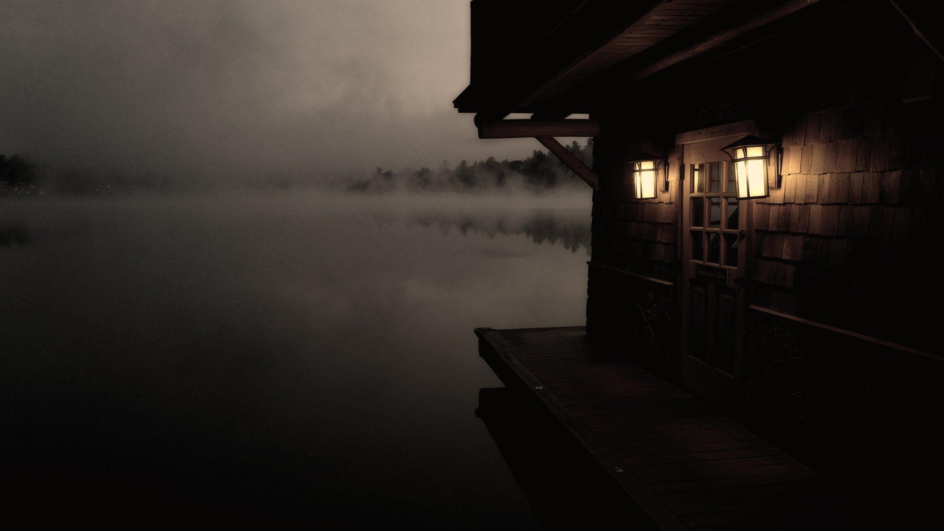 A house is sitting on a dock next to a lake at night.
