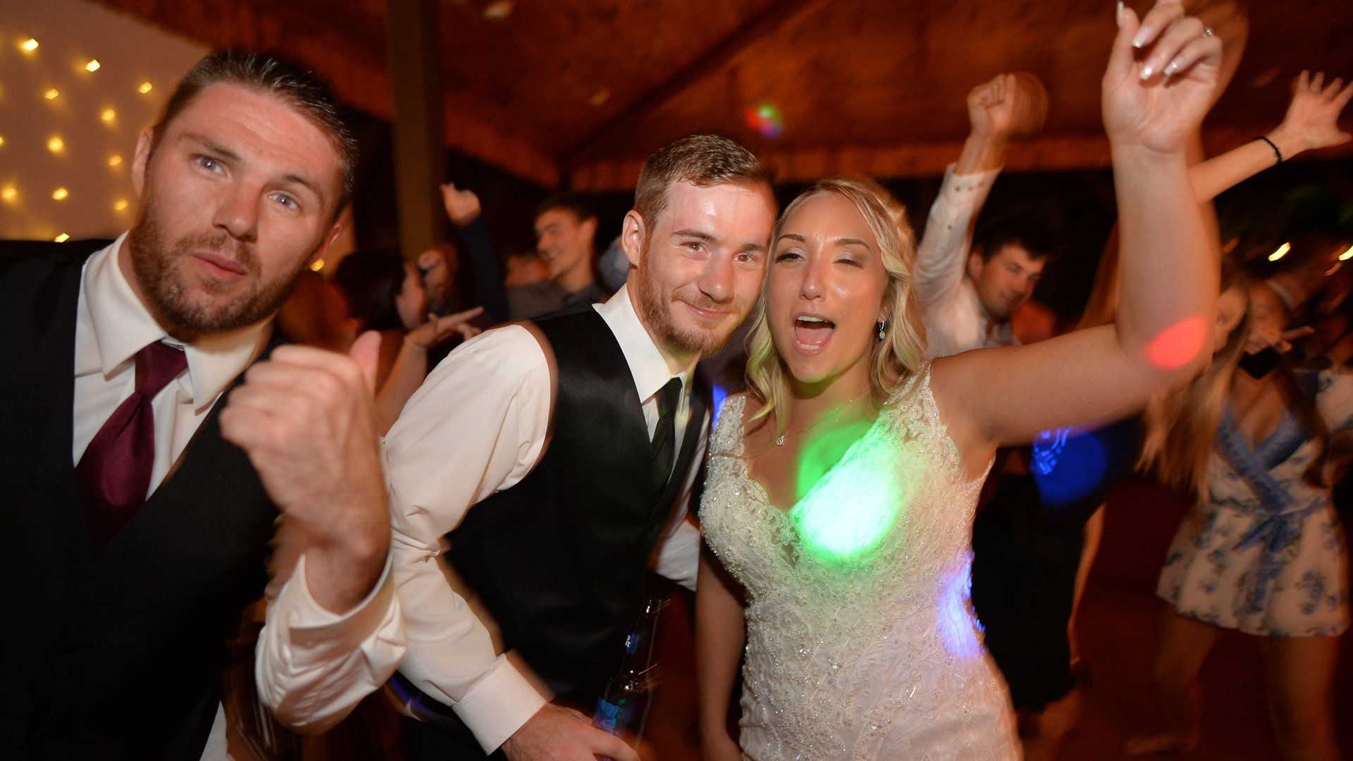 A bride and groom are dancing with their friends at a wedding reception.