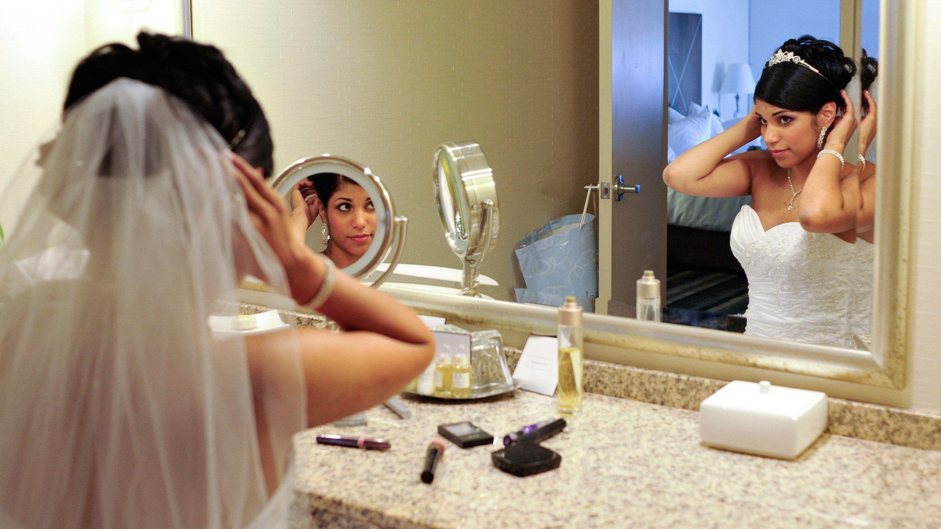 A bride is getting ready in front of a mirror in a bathroom.