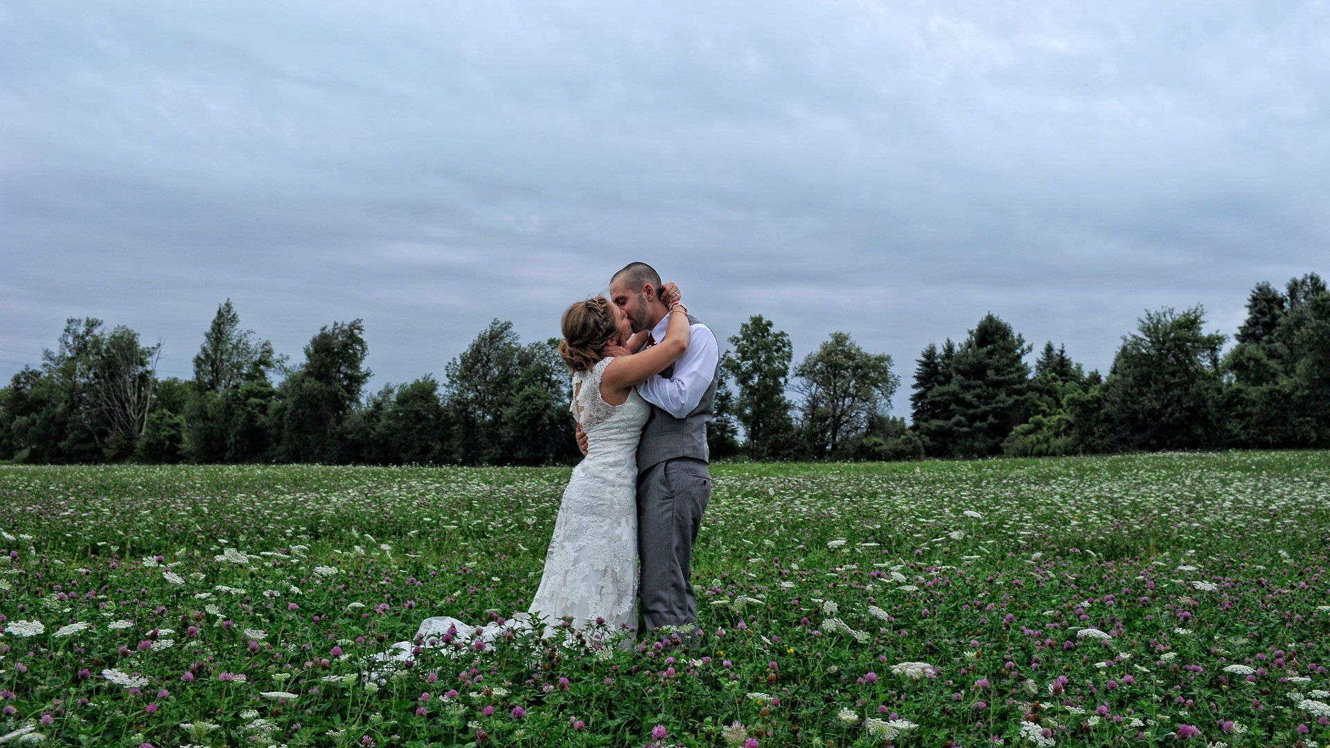 A bride and groom are kissing in a field of flowers.