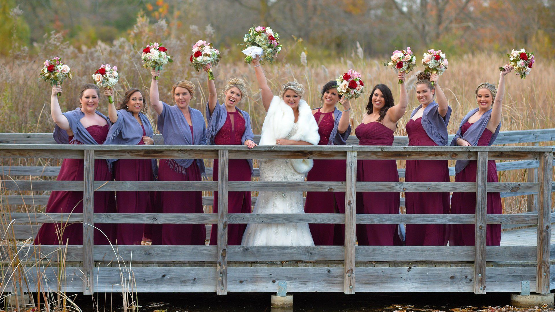 A bride and her bridesmaids are posing for a picture on a bridge.