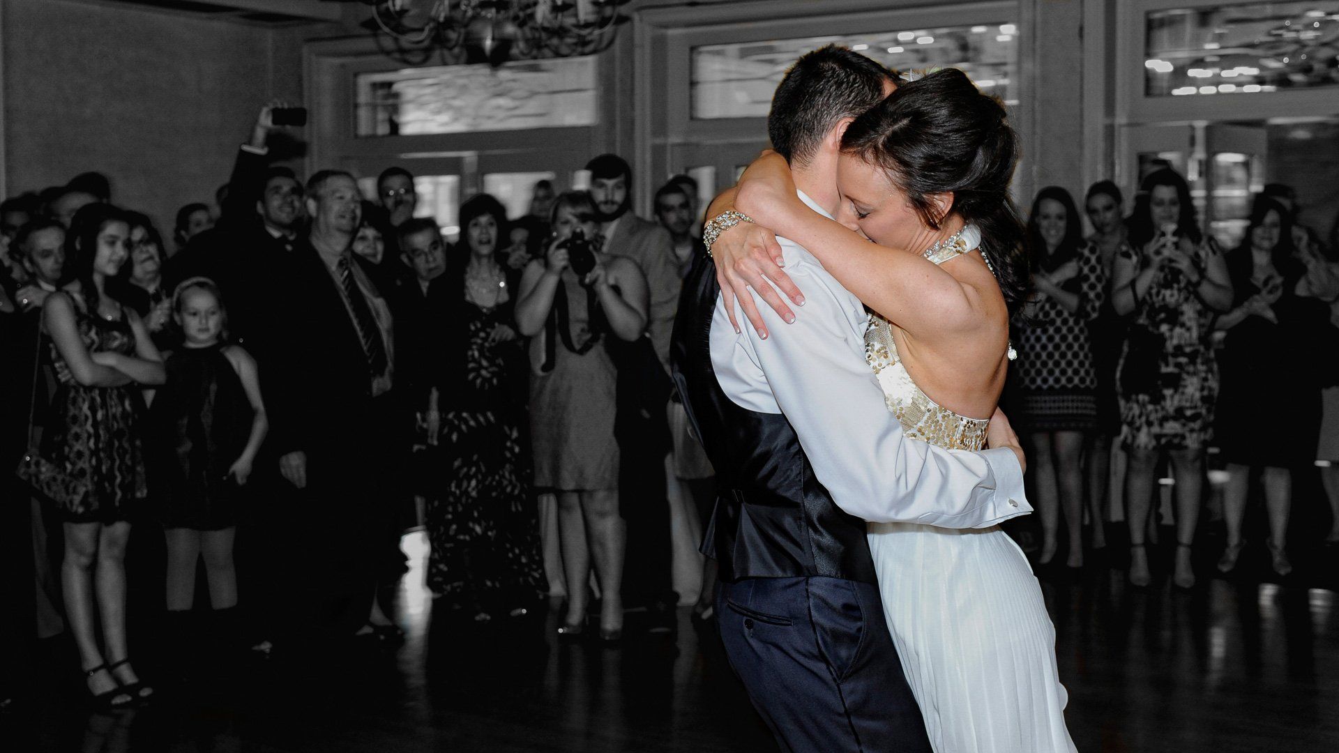 A bride and groom are dancing in front of a crowd at their wedding reception.