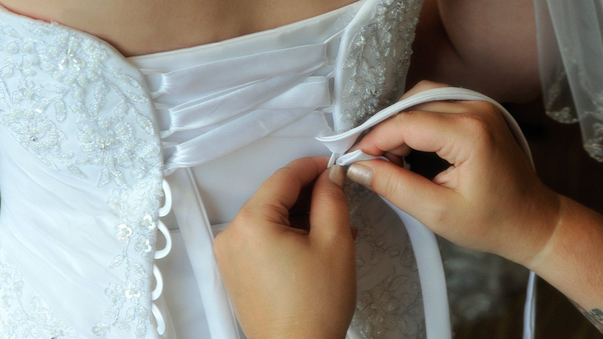 A woman is helping a bride with her wedding dress.