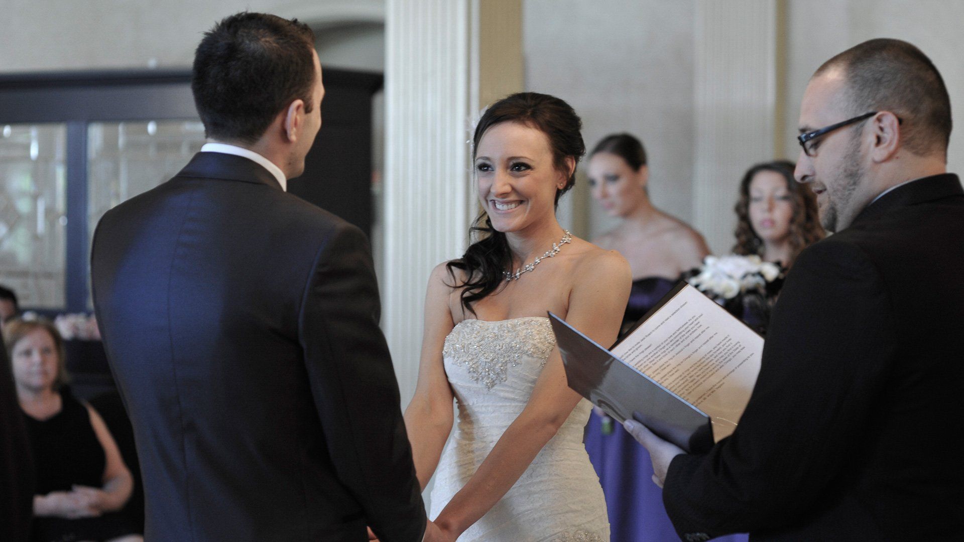 A bride and groom are holding hands during their wedding ceremony