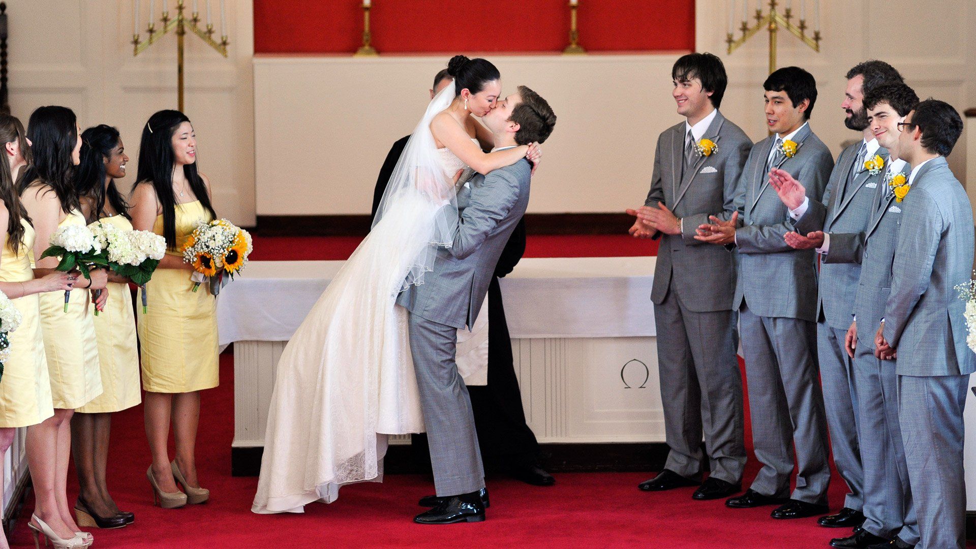 A bride and groom kissing in front of their wedding party