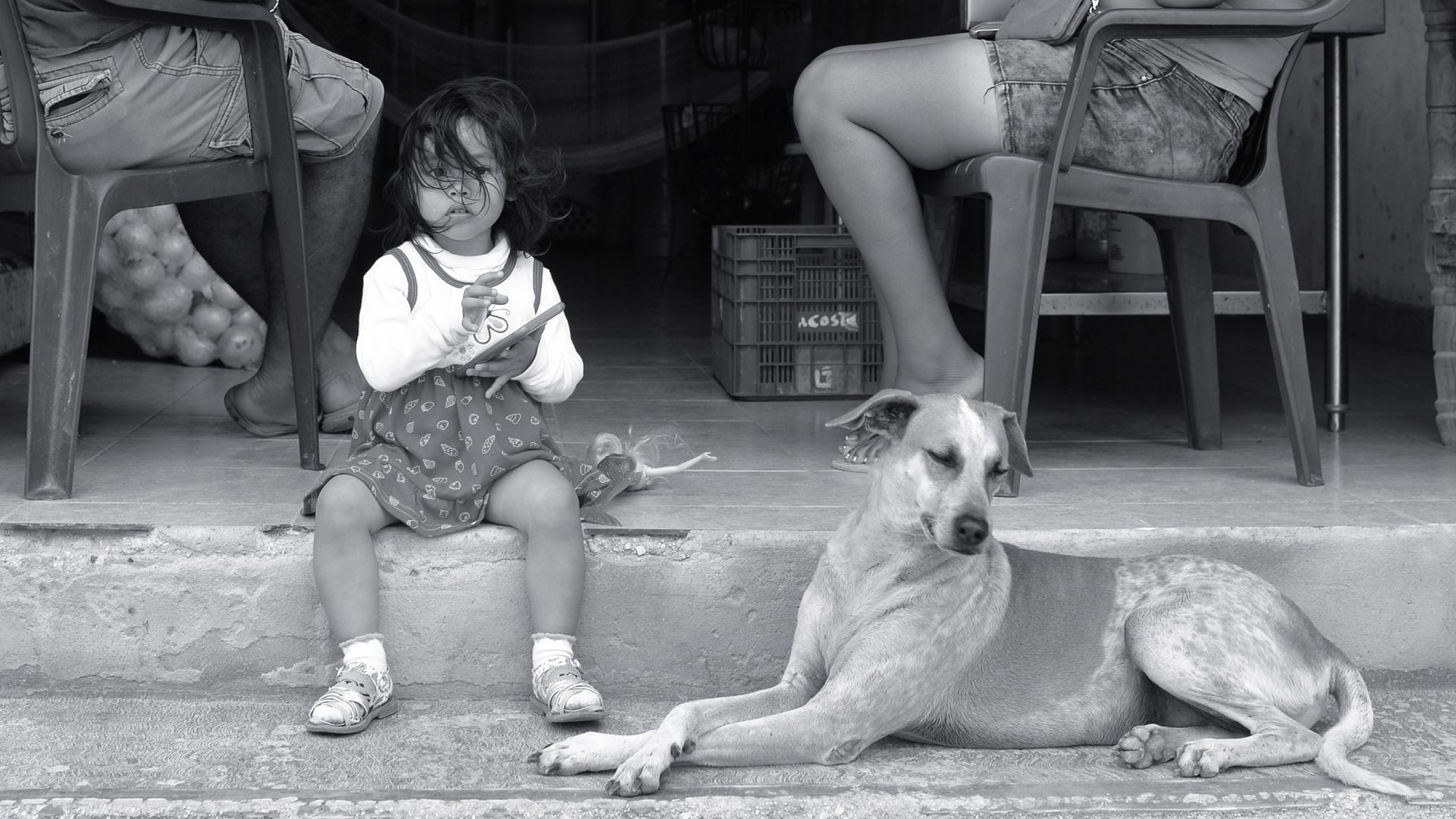 A woman is holding a white shirt in front of a man in a striped tank top.