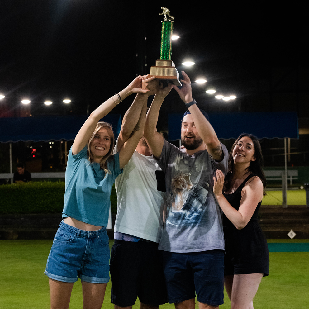 The winning team holds up their bowling trophy.