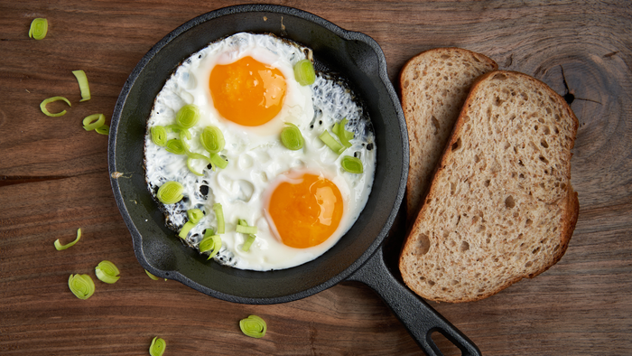 A skillet filled with eggs and bread on a wooden table.