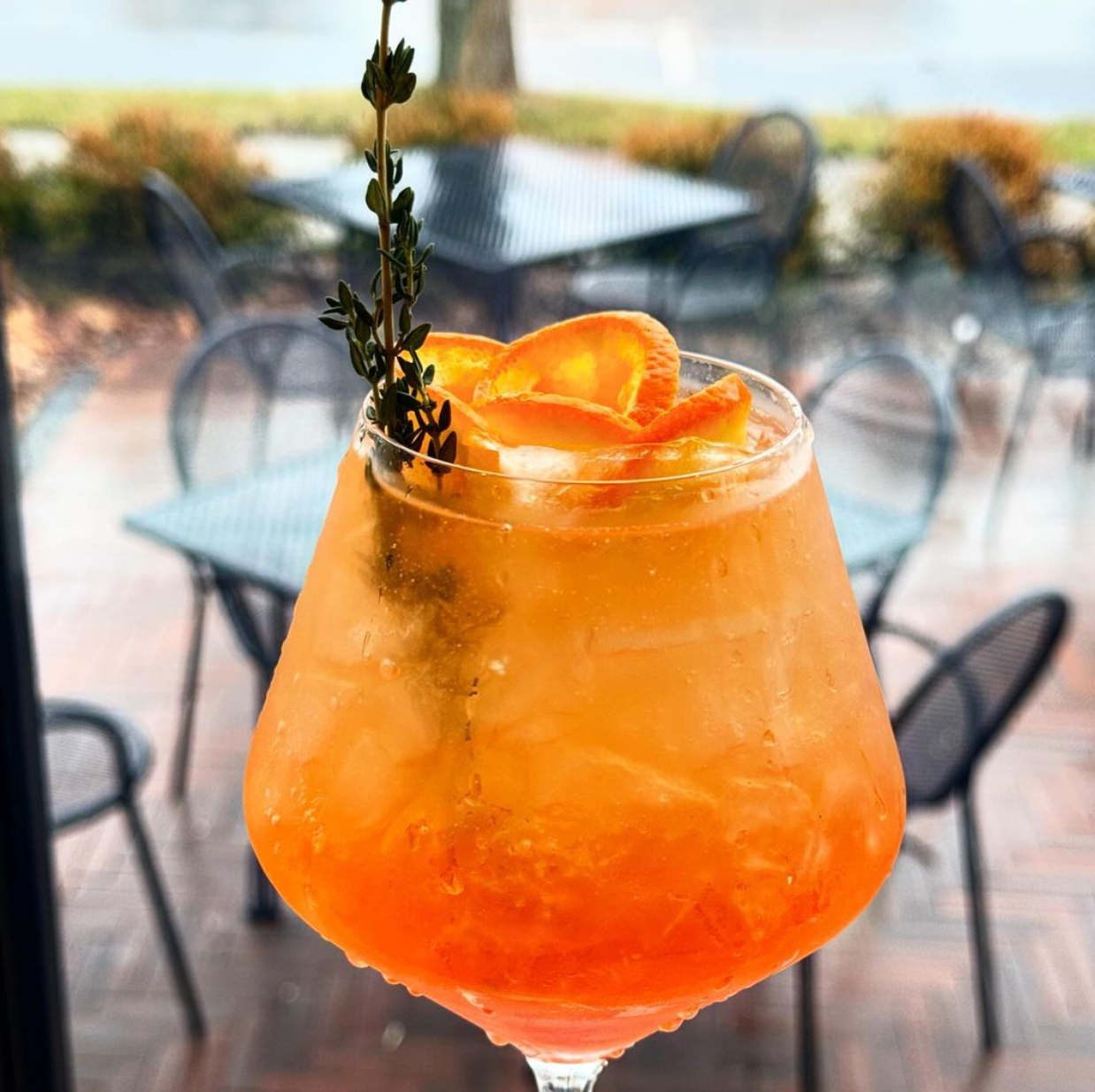 A close up of an orange drink in a wine glass