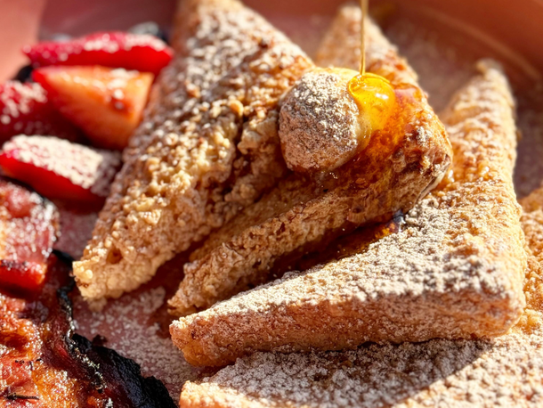 A close up of french toast with syrup and strawberries on a plate.