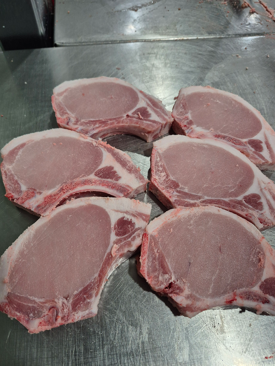 A bunch of pork chops are sitting on a table.