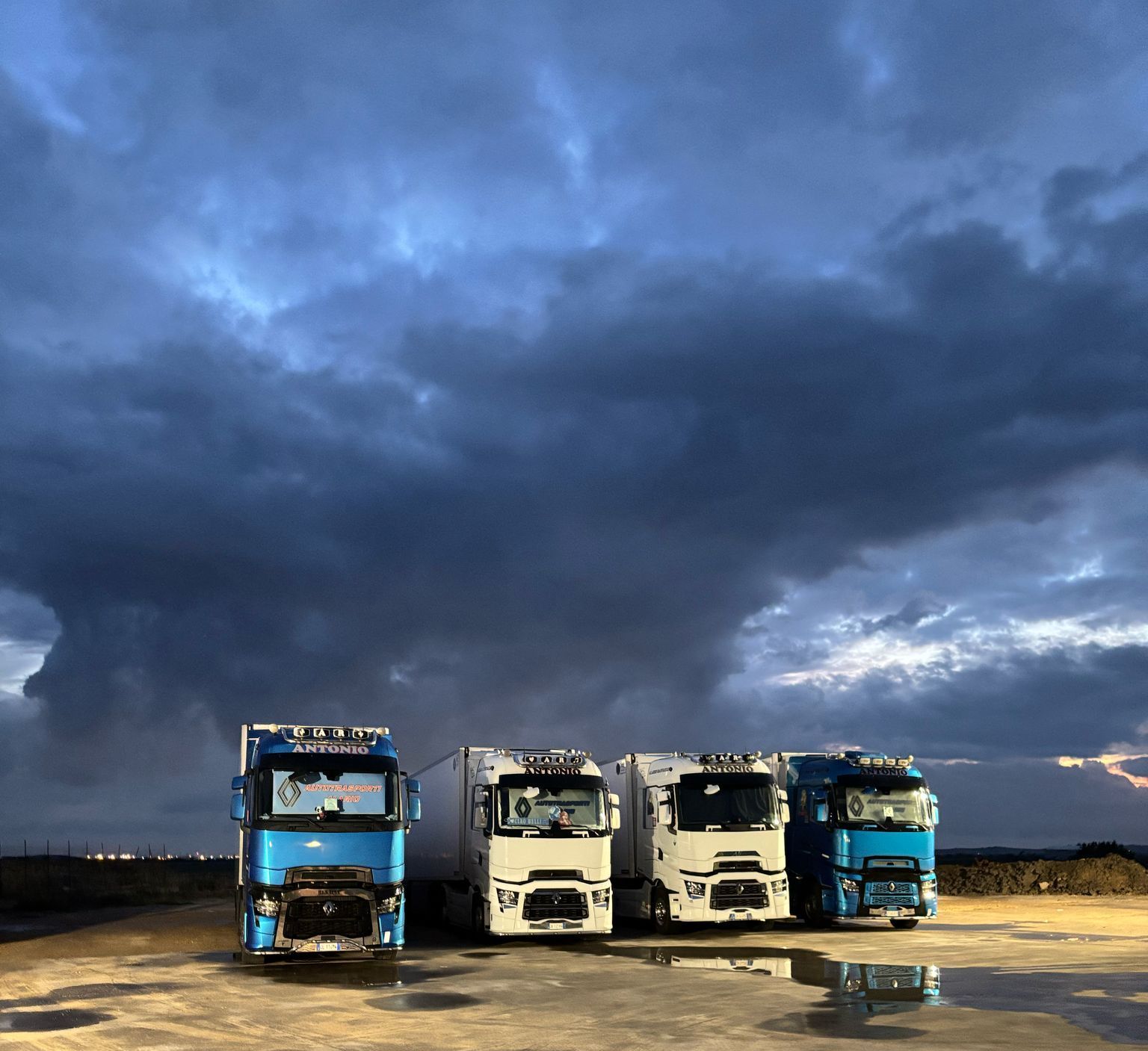 Tre camion sono parcheggiati in un parcheggio sotto un cielo nuvoloso