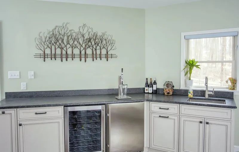 A kitchen with white cabinets, a stainless steel refrigerator, and a sink.