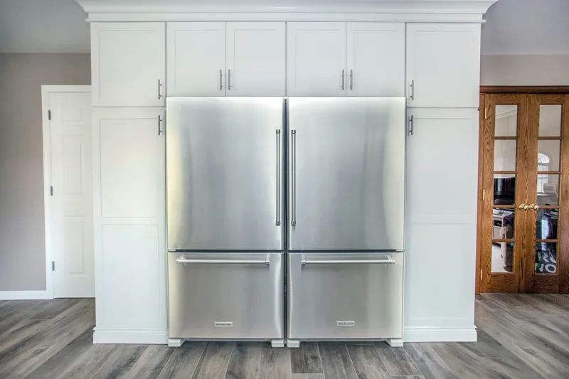 A stainless steel refrigerator and freezer are built into a wall in a kitchen.