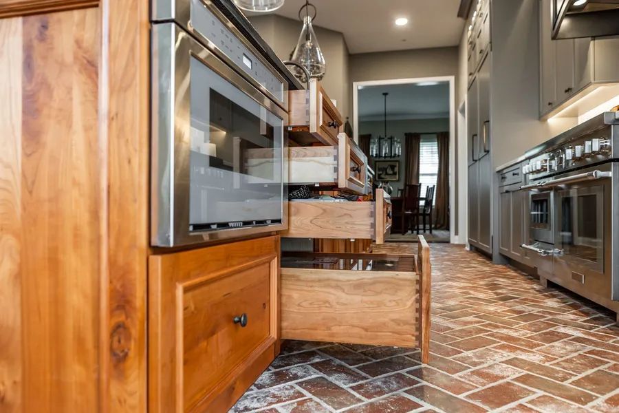 A kitchen with stainless steel appliances and wooden cabinets and drawers.