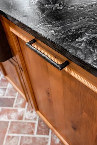 A kitchen with wooden cabinets and a black granite counter top.