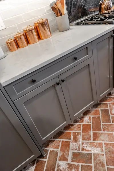 A kitchen with gray cabinets and copper canisters on the counter.