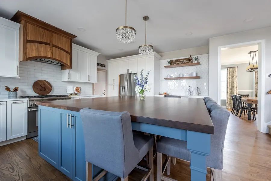 A kitchen with blue cabinets and a large island with a wooden counter top.