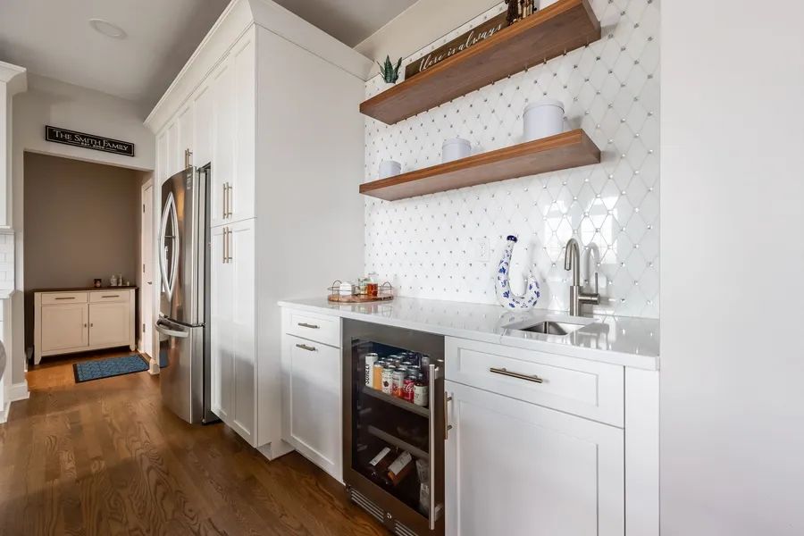 A kitchen with white cabinets, stainless steel appliances, wooden shelves and a refrigerator.