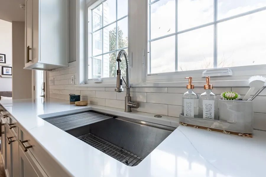 A kitchen sink with a faucet and soap dispensers on the counter.