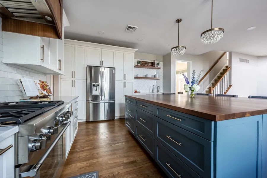 A kitchen with blue cabinets, stainless steel appliances, and a large island.