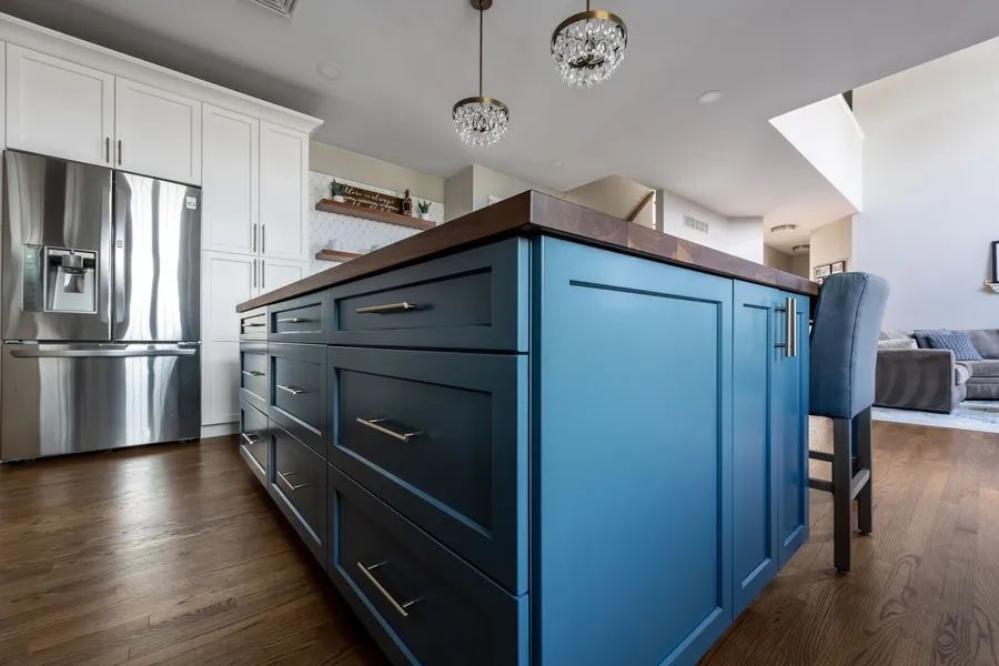A kitchen with blue cabinets and a large island in the middle.