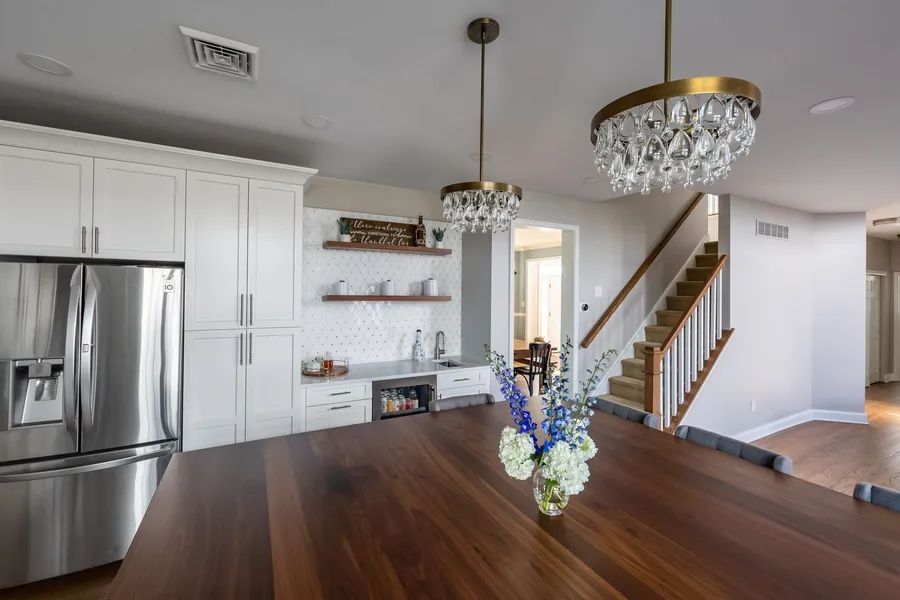 A kitchen with a large wooden table and a staircase.