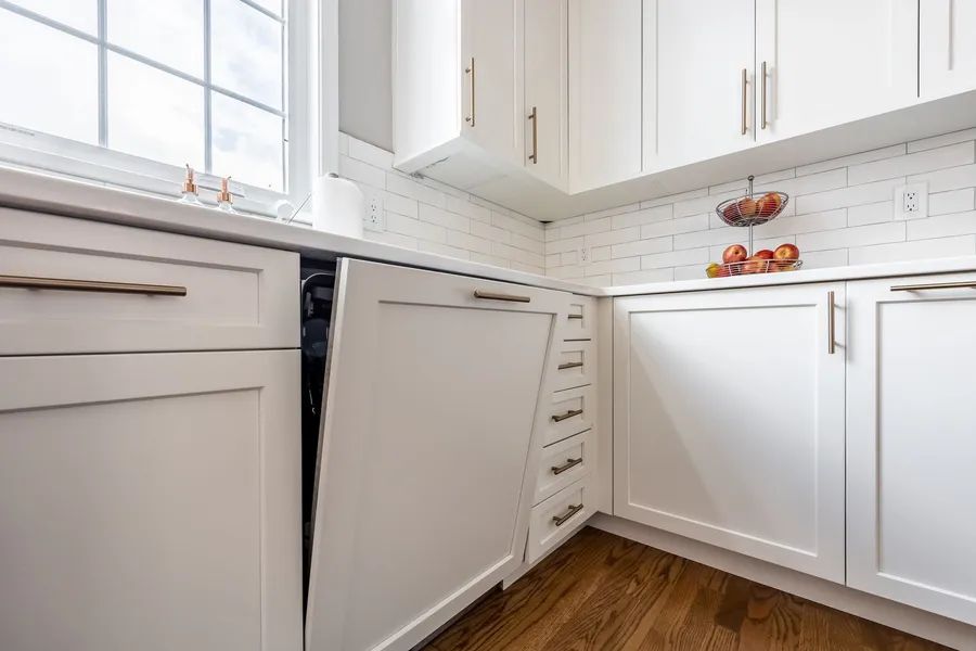A kitchen with white cabinets and a dishwasher.