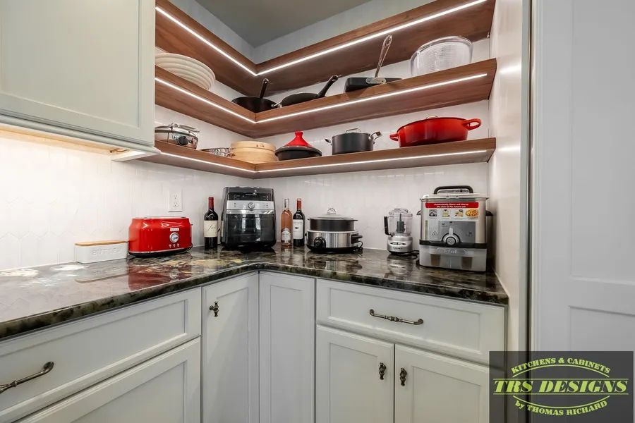 A kitchen with white cabinets, granite counter tops, and wooden shelves.