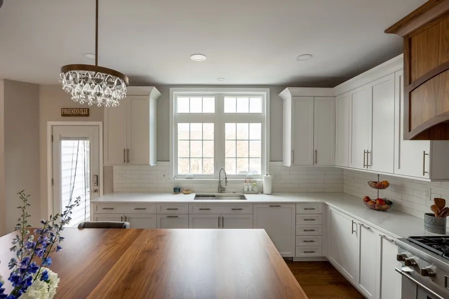 A kitchen with white cabinets and a wooden table.