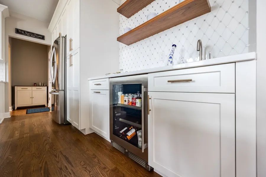 A kitchen with white cabinets and a stainless steel refrigerator.