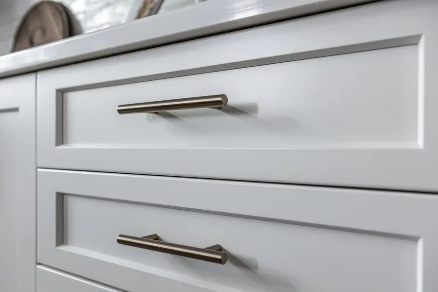 A close up of a white cabinet with stainless steel handles.