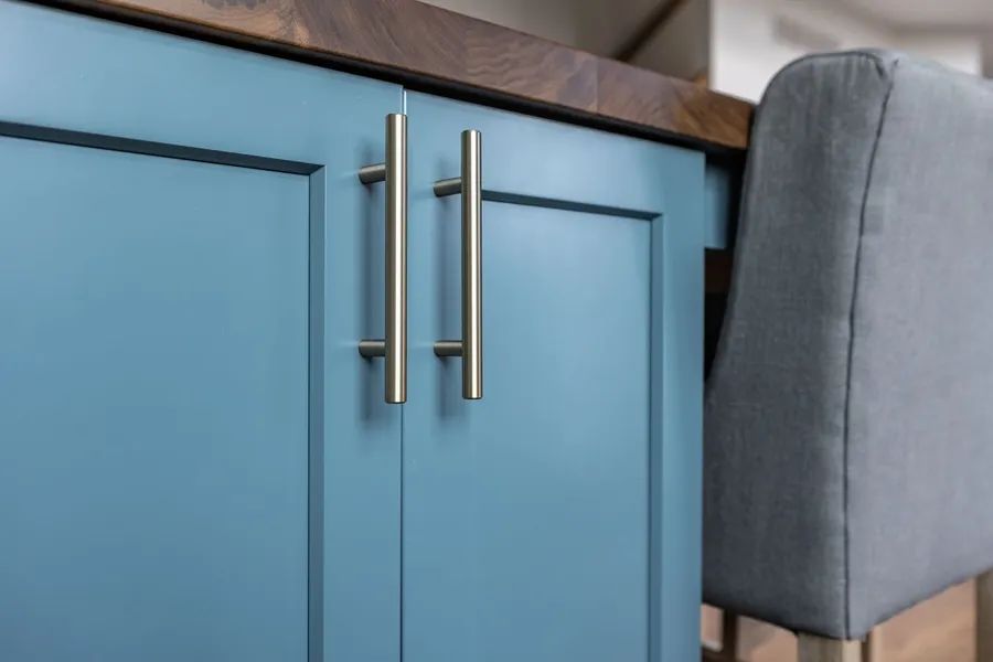 A kitchen with blue cabinets and a gray chair.