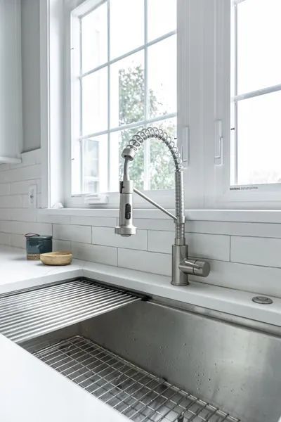 A kitchen sink with a faucet and a window in the background.