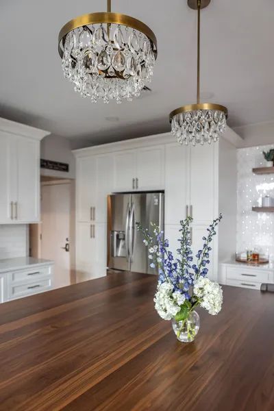 There is a vase of flowers on the counter in the kitchen.