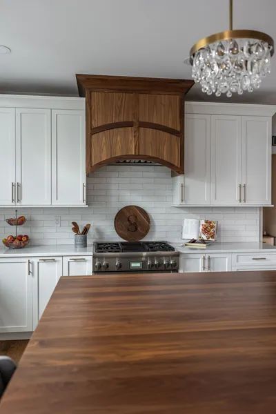 A kitchen with white cabinets and a wooden table.