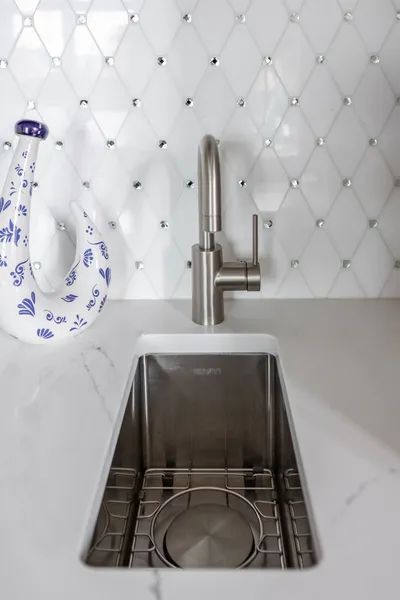 A kitchen sink with a faucet and a vase on the counter.