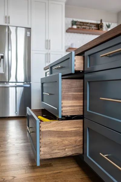 A kitchen with wooden drawers and a stainless steel refrigerator.