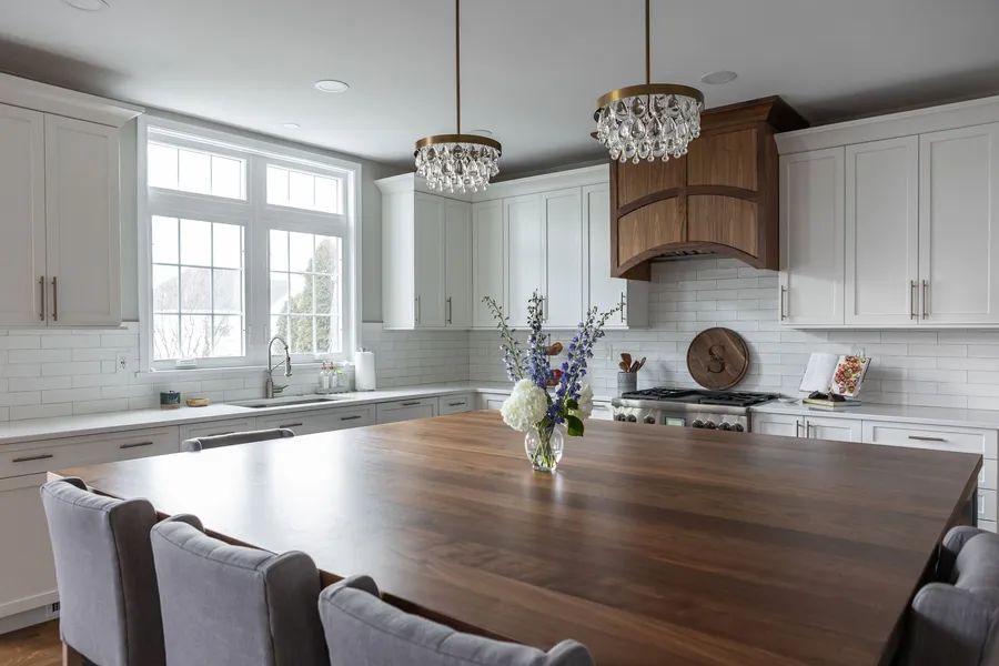There is a large wooden table in the middle of the kitchen.