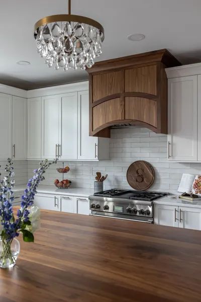 A kitchen with white cabinets and a wooden counter top.