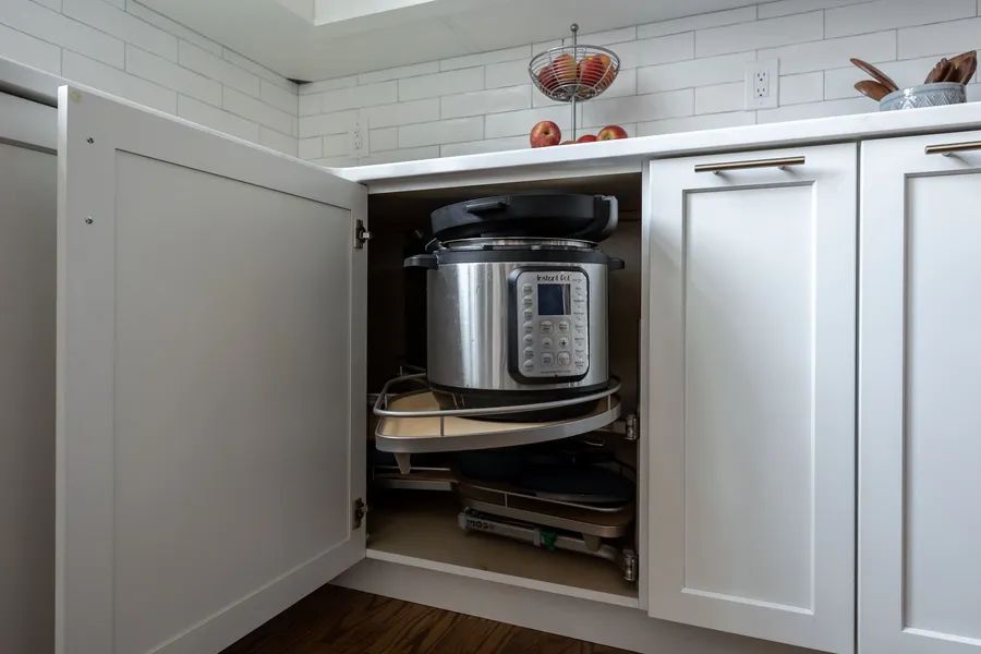 An instant pot is sitting inside of a kitchen cabinet.