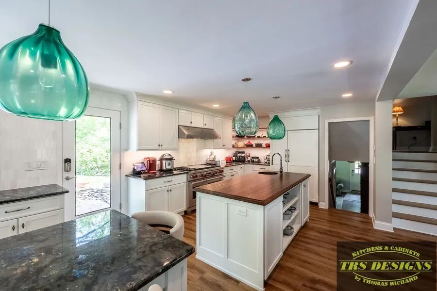 A kitchen with white cabinets and a large island in the middle.