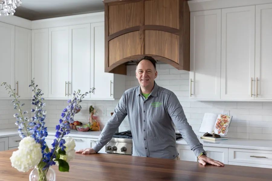 A man is leaning on a counter in a kitchen.