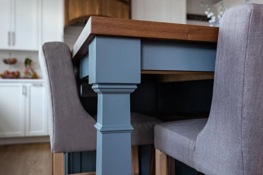 A dining room table and chairs in a kitchen with a blue table leg.