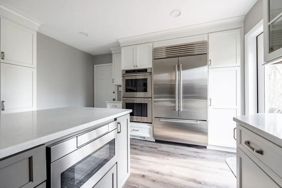 A kitchen with stainless steel appliances and white cabinets.
