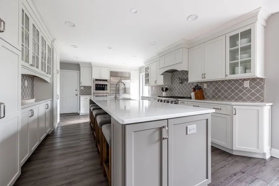 A kitchen with white cabinets and a large island in the middle.
